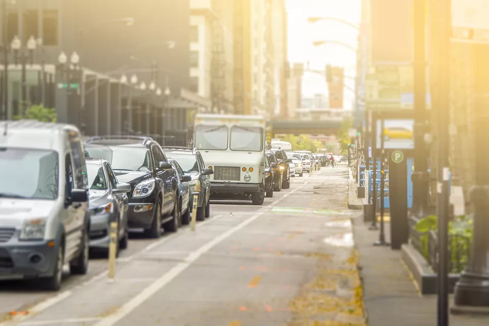 Bike lane and line of cars on street in Chicago with sun in background